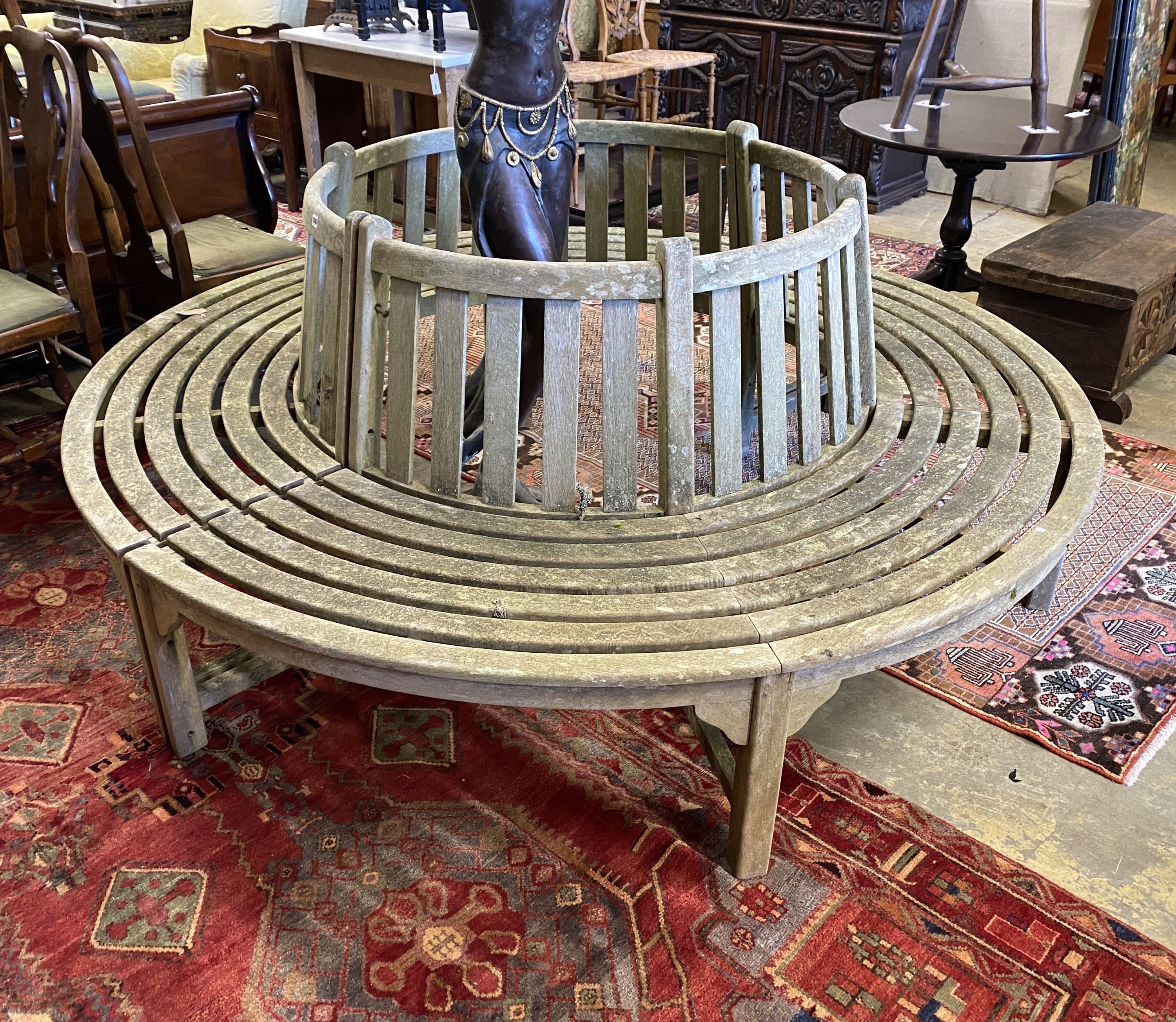 A weathered teak sectional circular garden tree seat, aperture approx. 106cm, seat diameter 220cm, height 88cm